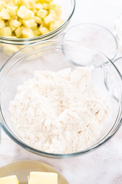 Abgemessene Zutaten in einer Glasrührschüssel zum Backen von Apfelkuchen mit Karamellglasur.