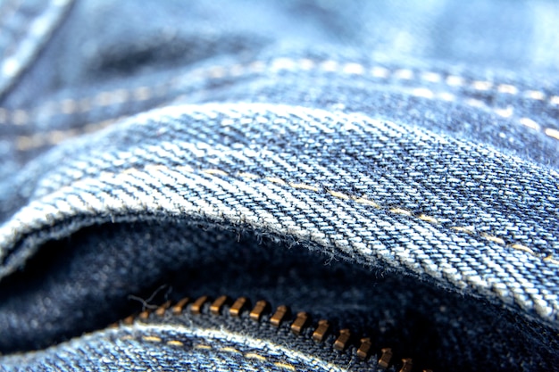 Abgenutzte blaue Denimjeansbeschaffenheit mit Reißverschluss / abstraktem Jeansbeschaffenheitshintergrund