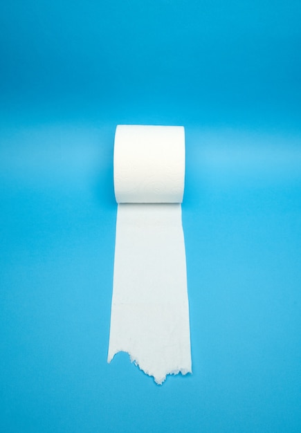 Abgerissene weiße Toilettenpapierrolle auf minimalistischem blauem Hintergrund