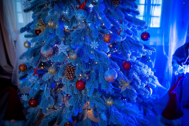 Abgeschnittene ansicht des schönen weihnachtsbaums mit lichtern und bändern erstaunlicher tannenbaum, der mit weihnachtskugeln geschmückt ist