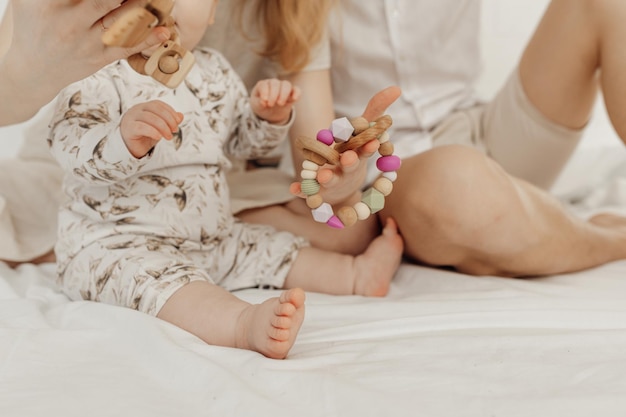 Abgeschnittene Ansicht einer Familie mit einem rundlichen Kleinkind, das einen modernen, umweltfreundlichen Beißring aus Holz hält