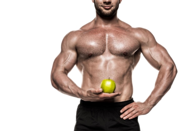 Abgeschnittene Ansicht eines verschwitzten muskulösen Sportlers mit grünem Apfel isoliert auf weißer gesunder Ernährung