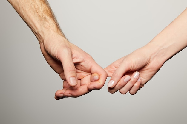 Abgeschnittene Ansicht von Mann und Frau, die die Finger isoliert auf Weiß halten