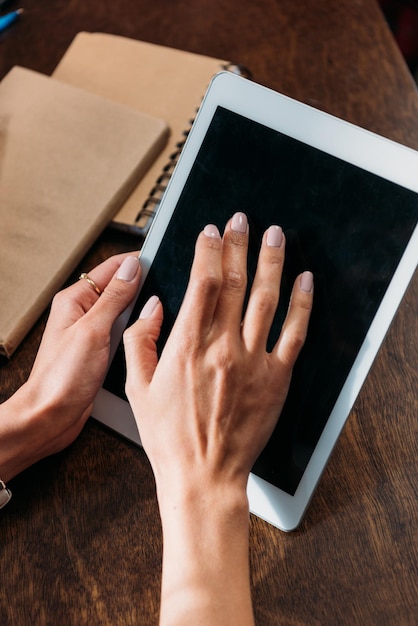 Abgeschnittene Aufnahme einer Frau, die ein digitales Tablet mit leerem Bildschirm auf der Tischplatte verwendet