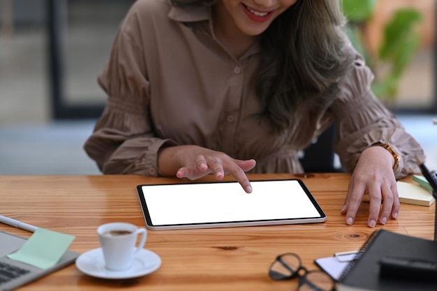 Abgeschnittene Aufnahme lächelnde Designerin mit digitalem Tablet auf Holzschreibtisch