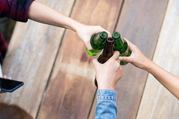 Abgeschnittene Aufnahme von Leuten, die Biergläser in der Sommercampingparty im Freien halten. Freunde, die beim Camping im Freien eine Flasche Bier klirren