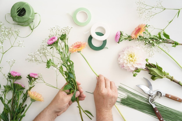 Foto abgeschnittene hände des blumenhändlers, die einen blumenstrauß auf dem tisch herstellen