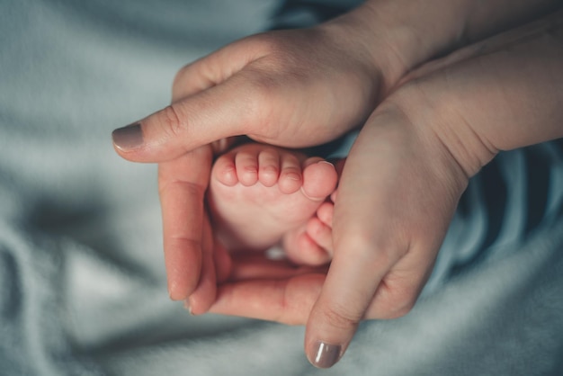 Abgeschnittene Hände einer Frau, die einen Jungen mit den Füßen auf dem Bett hält