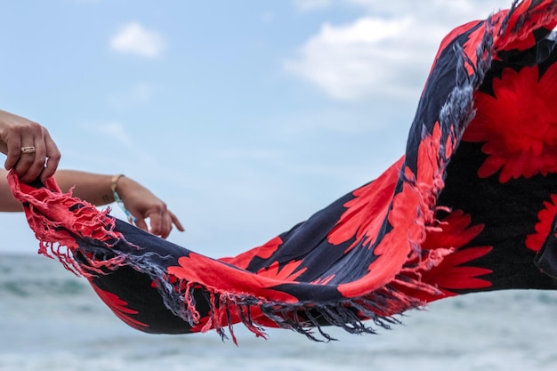 Foto abgeschnittene hände einer frau, die einen schal am strand hält