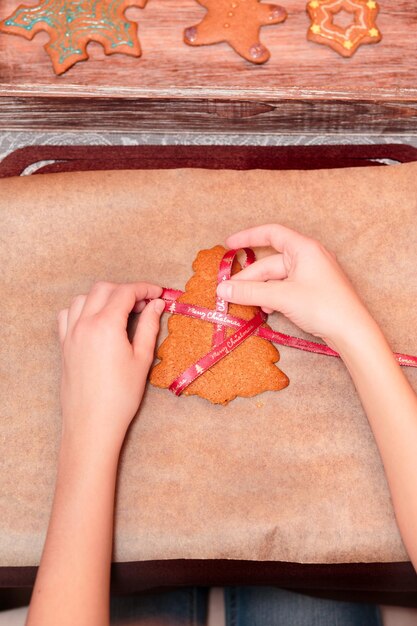 Foto abgeschnittene hände einer frau, die gingerbread-kekse auf dem tisch zubereitet