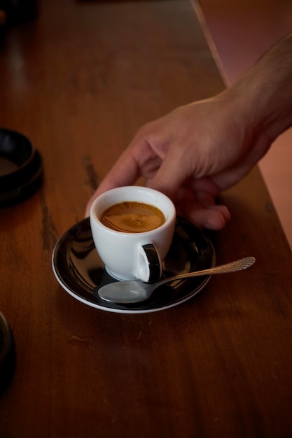 Abgeschnittene Hände einer Frau, die Kaffee auf dem Tisch hält