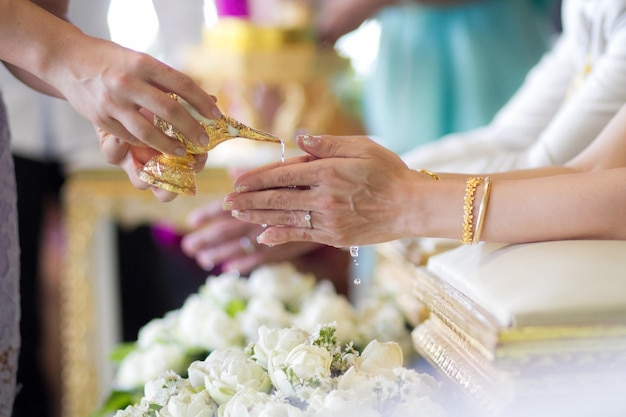 Abgeschnittene Hände einer Frau, die während der Hochzeit mit Bräutigam und Braut Rituale durchführt