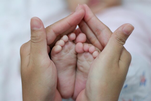 Foto abgeschnittene hände einer frau, die zu hause babyfüße hält
