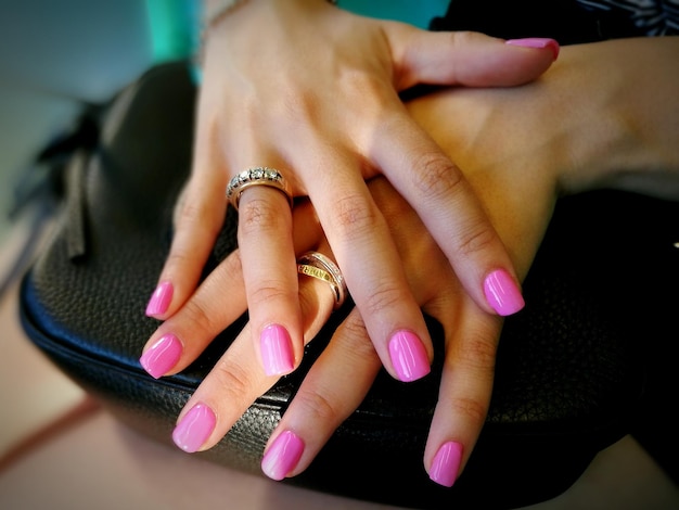 Abgeschnittene Hände einer Frau mit rosa Nagellack