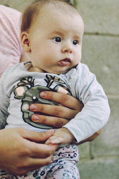 Foto abgeschnittene hände einer mutter, die ein süßes baby hält