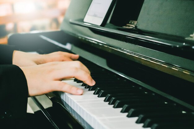 Abgeschnittene Hände einer Person, die Klavier spielt