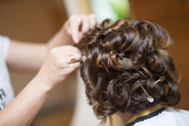 Abgeschnittene Hände eines Friseurs, der eine weibliche Kundin im Friseursalon stylt