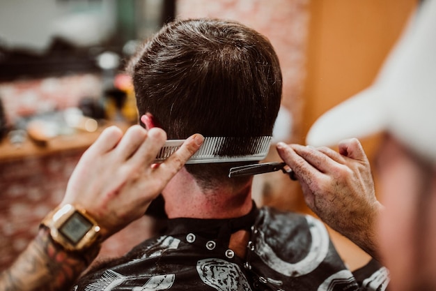 Abgeschnittene Hände eines Friseurs, der einen Kunden im Salon pflegt