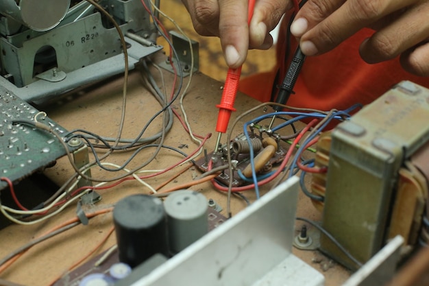 Abgeschnittene Hände eines männlichen Technikers, der ein Radio repariert