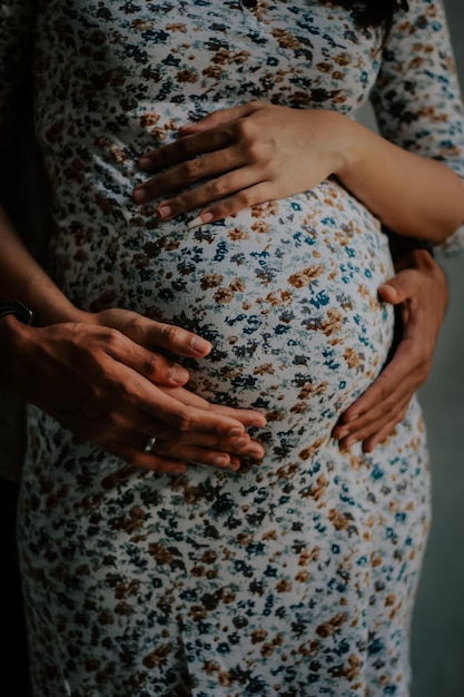 Abgeschnittene Hände eines Mannes berühren den Bauch einer schwangeren Frau