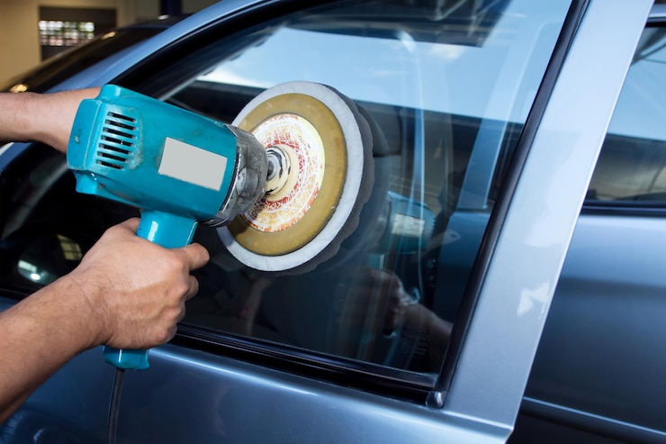 Foto abgeschnittene hände eines mannes, der ein autofenster in einer autoreparaturwerkstatt polierte