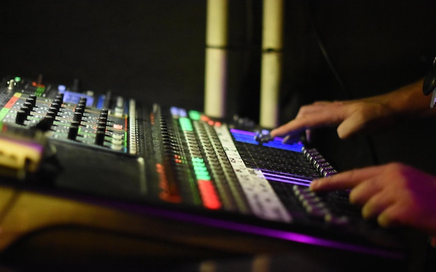 Abgeschnittene Hände eines Mannes, der in einem Nachtclub Soundmixer spielt
