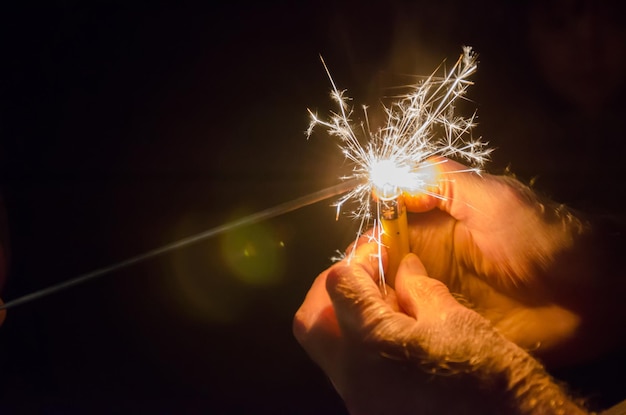 Abgeschnittene Hände eines Mannes, der nachts mit einem Zigarettenzünder einen Funken entzündet