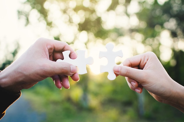 Abgeschnittene Hände halten in einem Park Puzzle-Stücke