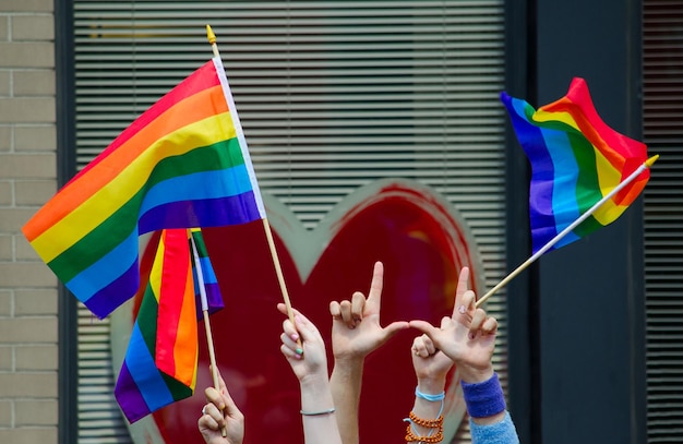 Abgeschnittene Hände von Frauen, die Regenbogenfahnen in der Stadt halten