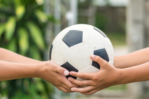 Foto abgeschnittene hände von freunden, die einen fußball im freien halten