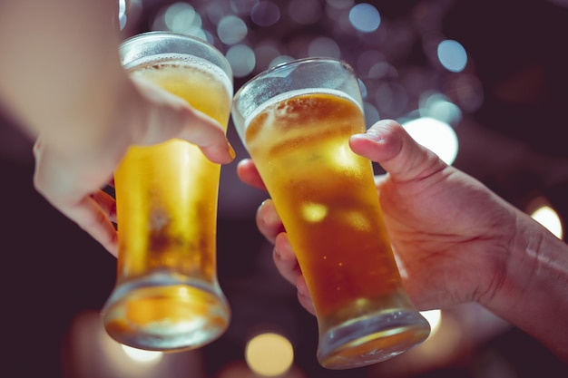 Abgeschnittene Hände von Leuten, die in einer Bar Biergläser toasten