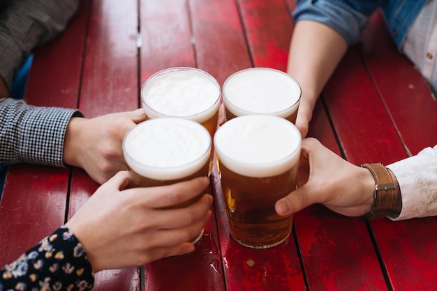 Foto abgeschnittene hände von männern und frauen, die biergläser am tisch halten