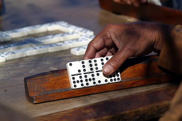 Foto abgeschnittene hand, die dominos auf einem holzstock hält