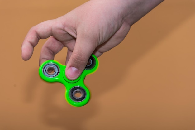 Abgeschnittene Hand, die einen Spinner gegen einen braunen Hintergrund hält