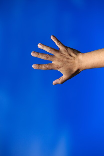 Foto abgeschnittene hand, die gegen den blauen himmel gestikuliert