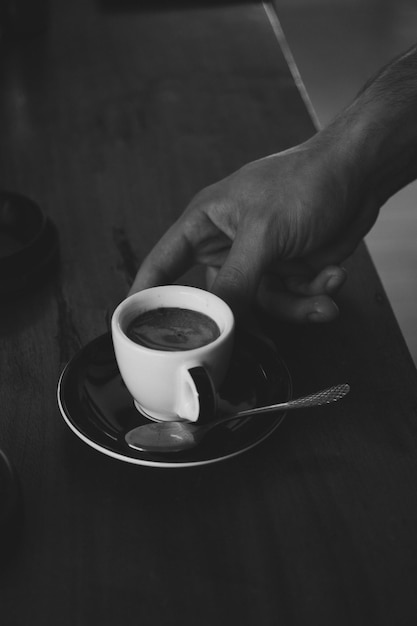Abgeschnittene Hand, die Kaffee auf dem Tisch hält