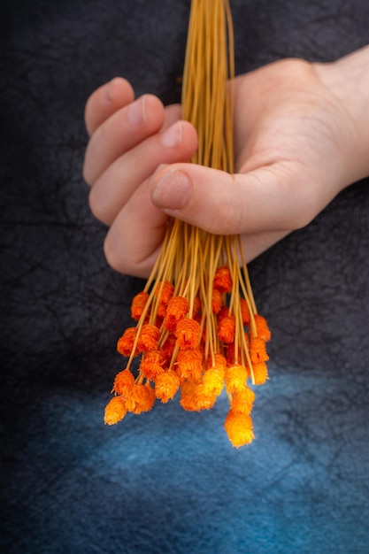 Foto abgeschnittene hand, die orangenblumen auf dem boden hält