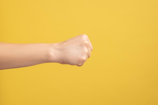 Abgeschnittene Hand einer Frau auf gelbem Hintergrund