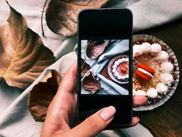 Foto abgeschnittene hand einer frau, die dessert auf dem tisch fotografiert