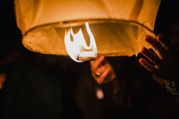 Foto abgeschnittene hand einer frau, die nachts laternen anzündet