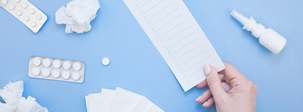 Foto abgeschnittene hand einer frau, die papier vor blauem hintergrund hält