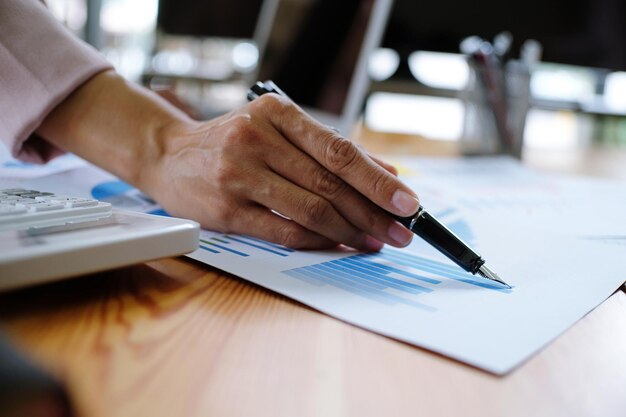 Foto abgeschnittene hand einer geschäftsfrau, die im büro über eine grafik arbeitet