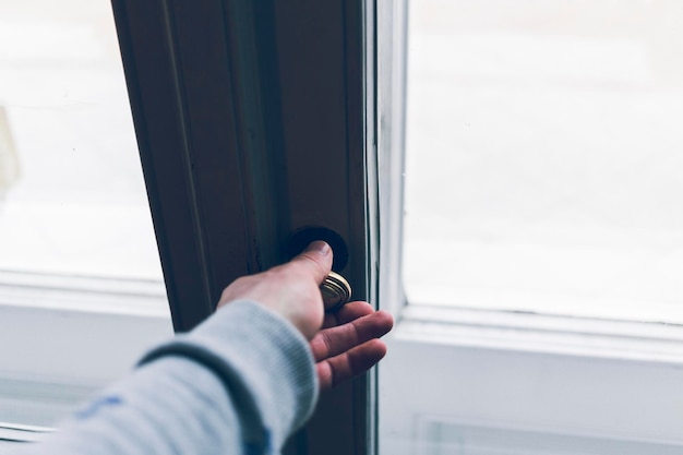 Abgeschnittene Hand einer Person, die den Fensterknopf hält