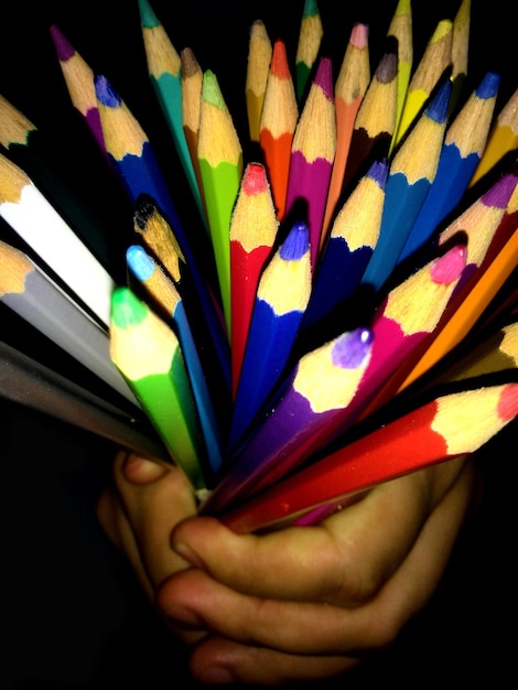 Abgeschnittene Hand einer Person, die farbige Bleistifte hält