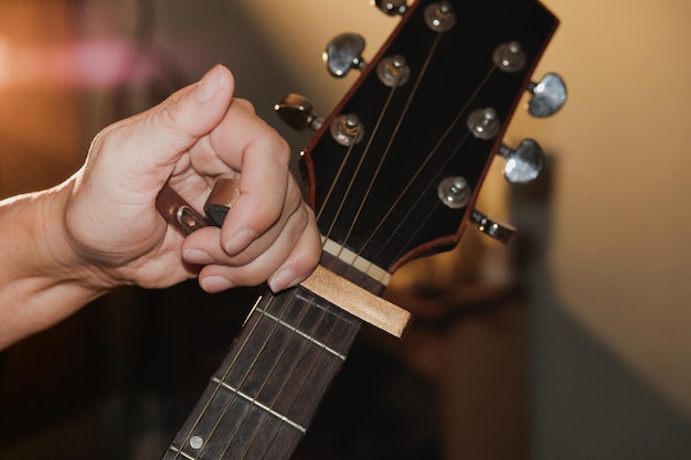 Abgeschnittene Hand einer Person, die Gitarre einstellt.