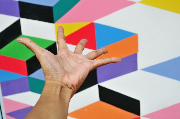 Foto abgeschnittene hand einer person, die in richtung farbenfroher wand gestimmt