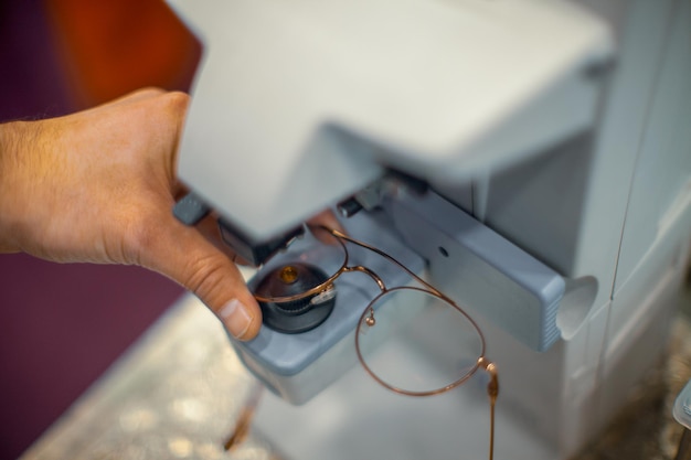 Abgeschnittene Hand eines Mannes, der an einem optischen Instrument arbeitet