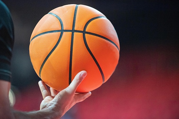 Abgeschnittene Hand eines Mannes, der auf dem Platz Basketball hält