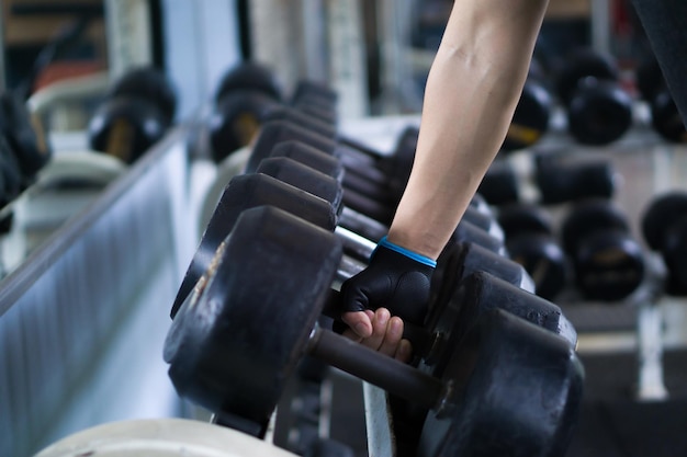 Abgeschnittene Hand eines Mannes, der eine Hantel im Fitnessstudio aufnimmt