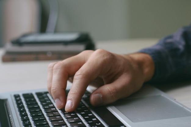 Abgeschnittene Hand eines Mannes, der einen Laptop auf dem Tisch benutzt